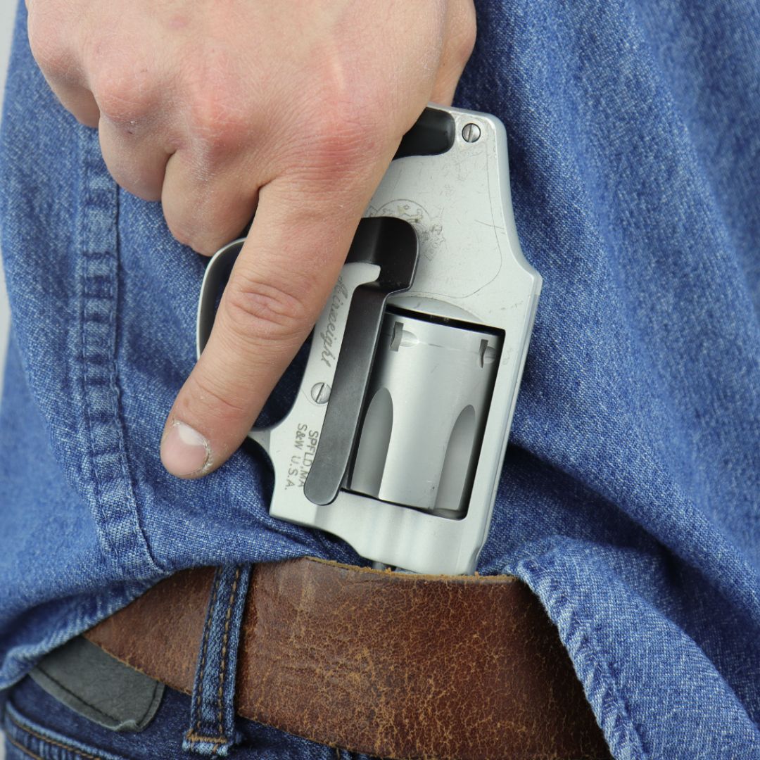 A person using a Clipdraw gunclip to wear their pistol inside the waistband on their jeans.