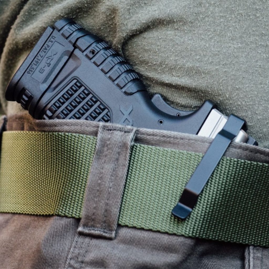 A person practicing concealed carry with a handgun that is outfitted with a Clipdraw belt clip.