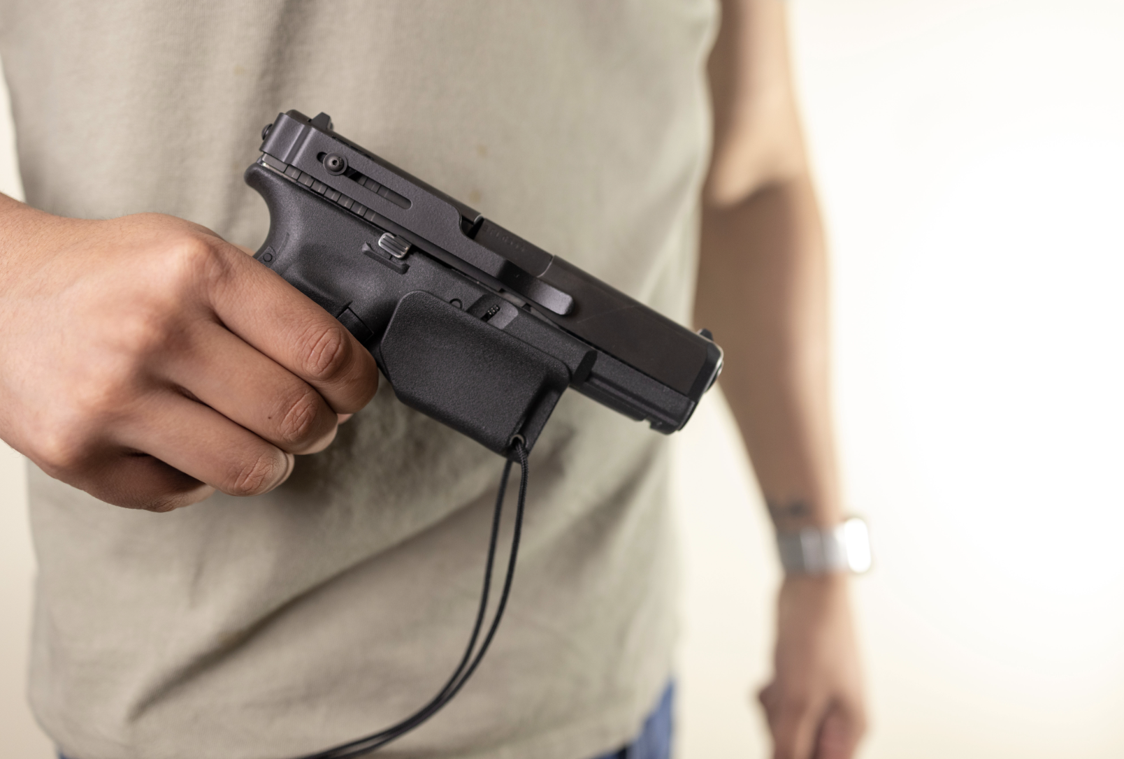 A close-up of a gun owner holding a firearm outfitted with a Clipdraw pistol trigger guard.